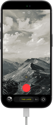 iPhone 18 Pro, Vorderseite, das Display zeigt eine Berglandschaft, mit der Kamera Modus Überlagerung im Zeitraffer Modus, mit dem Netzkabel am Ladeanschluss