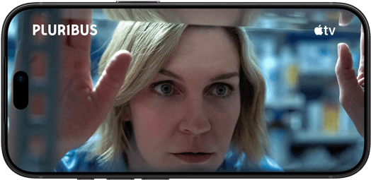 Ein iPhone 18 Pro im Querformat, das Display zeigt eine Nahaufnahme einer Frau, die aus einem Fenster schaut. Serienname: Pluribus