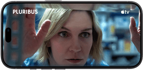 Ein iPhone 18 Pro im Querformat, das Display zeigt eine Nahaufnahme einer Frau, die aus einem Fenster schaut. Serienname: Pluribus