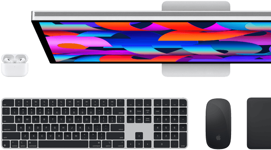 Draufsicht auf einen Studio Display Monitor, ein Magic Keyboard in Schwarz, eine Magic Mouse in Schwarz, ein Magic Trackpad in Schwarz und ein AirPods Case in Weiß