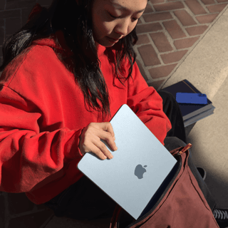 Eine Studentin steckt ein MacBook Air in den Rucksack