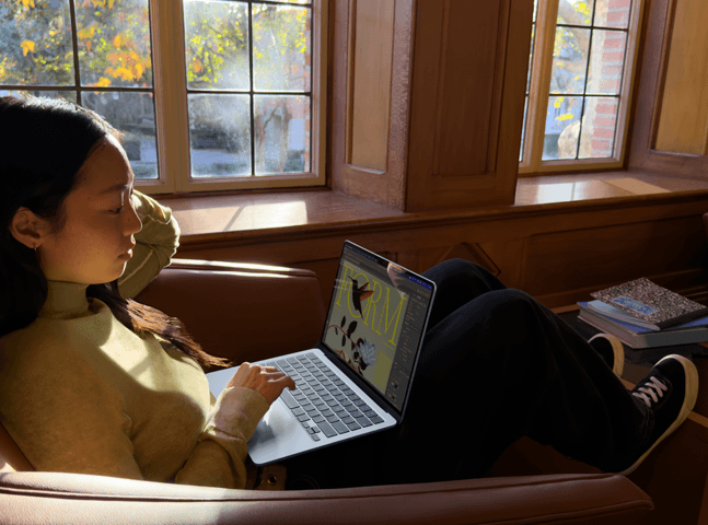 Eine Person sitzt auf einem Stuhl und arbeitet mit einem MacBook Air
