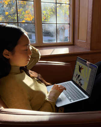 Eine Person sitzt auf einem Stuhl und arbeitet mit einem MacBook Air